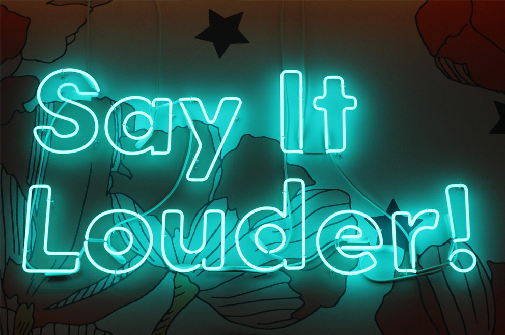 Neon-Schrift: "Say it louder!"