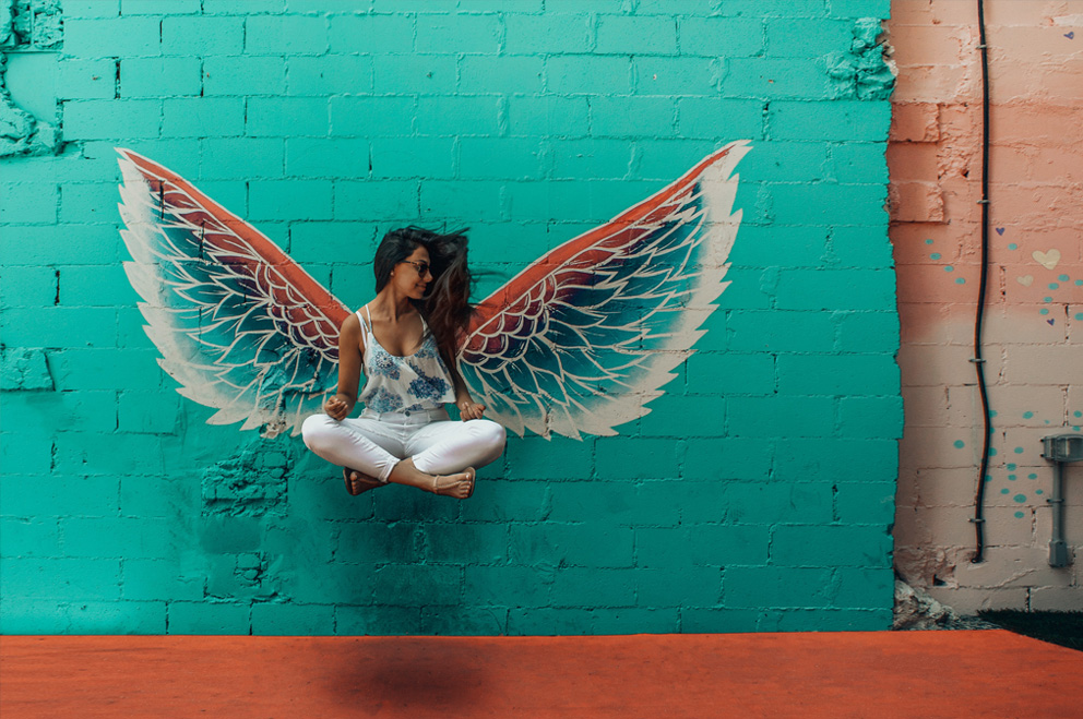 Junge Frau vor einem Graffito mit Flügeln.